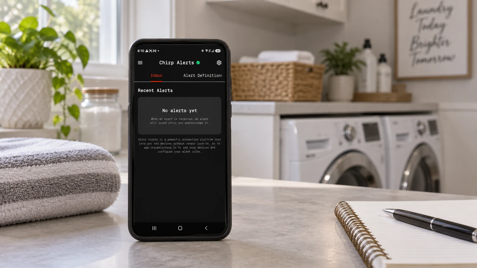 The documented empty CHIRP Alerts inbox displayed on an Android phone in an illustrated dry laundry room